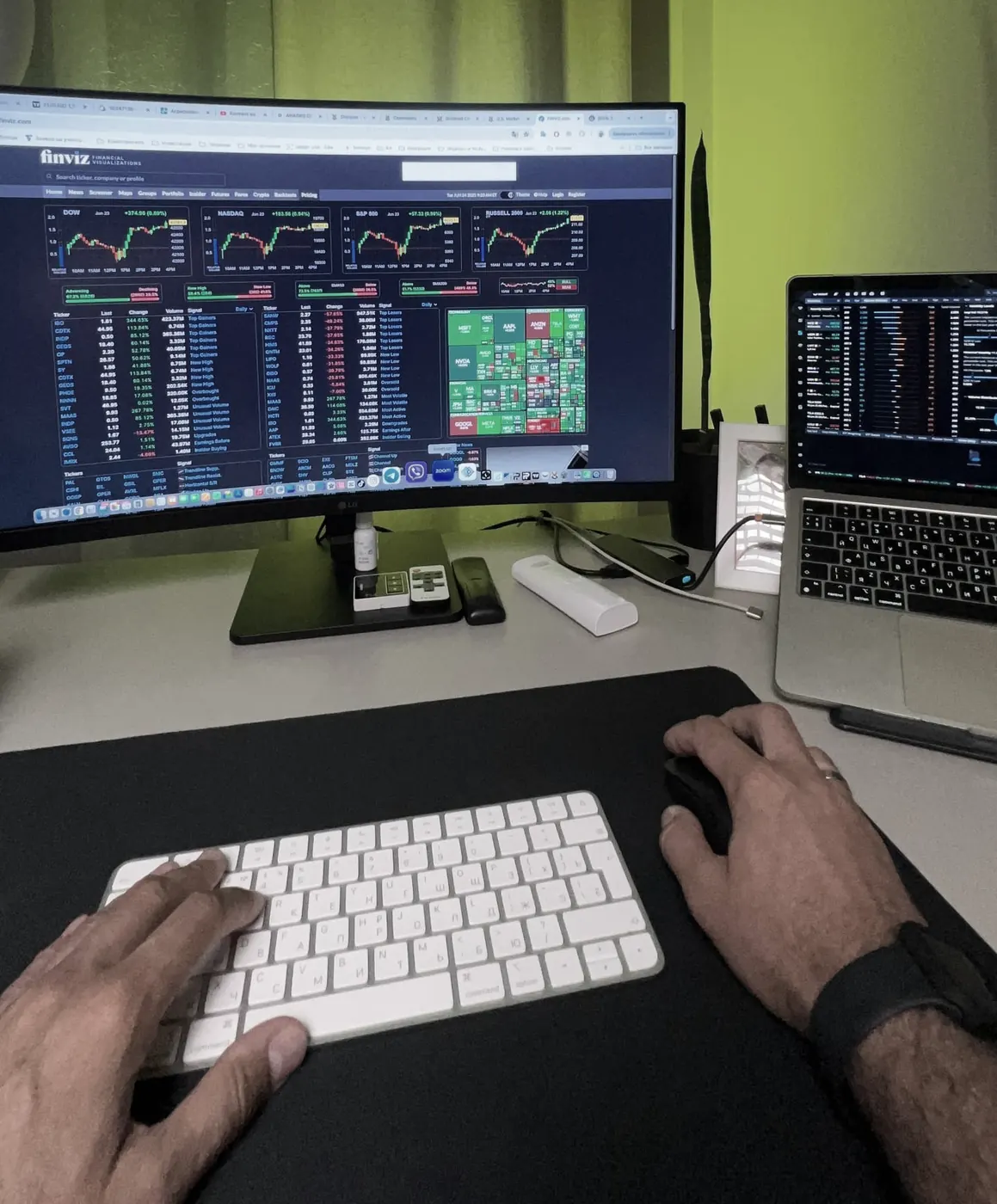 Рабочее место Михаила: монитор с обзором рынка на finviz, ноутбук и клавиатура